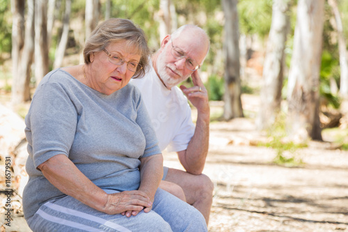 Upset Senior Woman Sits With Concerned Husband Outdoors photo