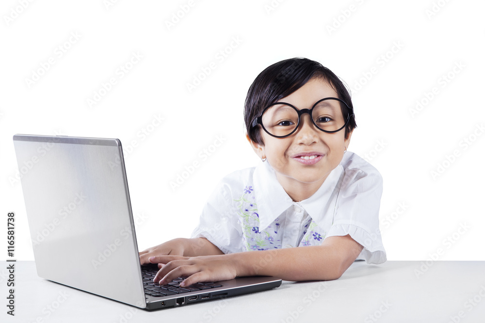 Attractive little girl uses laptop and smiling