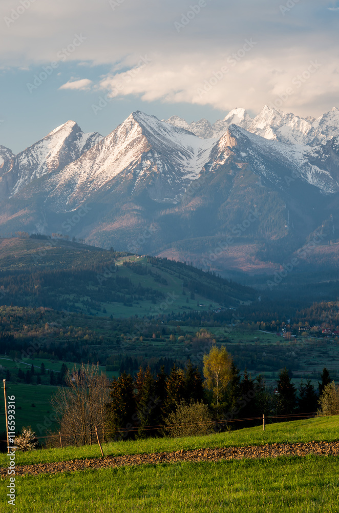 Fototapeta premium Beautiful spring panorama over Spisz highland to snowy Tatra mountains in the colorful morning, Poland