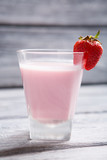 Glass with pink liquid. Strawberry on a glass. Cocktail of milk and strawberries. Dense and sweet beverage.