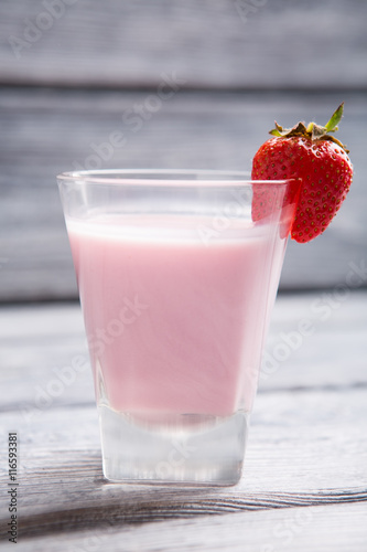 Glass with pink liquid. Strawberry on a glass. Cocktail of milk and strawberries. Dense and sweet beverage.