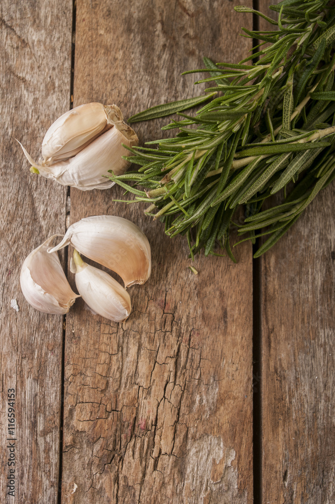 Composition of garlic and rosemary on wooden background, close up
