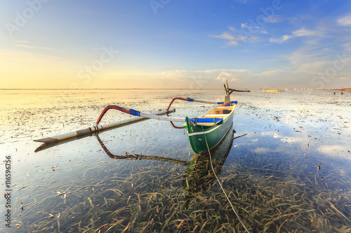Green fishing boats populate the shoreline at the Sanur Beach, Bali, indonesia photo
