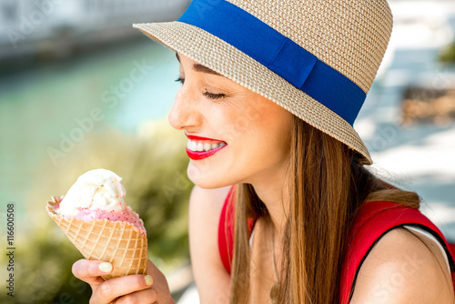 Young female tourist enjoying ice cream sitting near the water chanal in Ljubljana city center. Traveling in Slovenia and tasting street food
