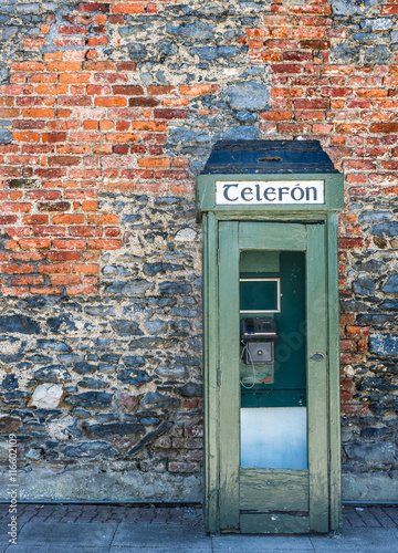 Old vintage Irish telephone box and brick wall texture in rural Ireland photo