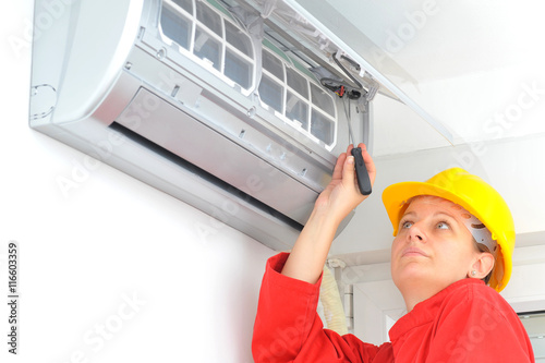 Woman worker adjusting air conditioner system