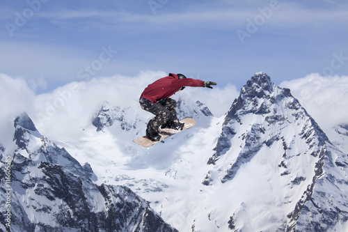 Snowboarder jumps high in the mountains.