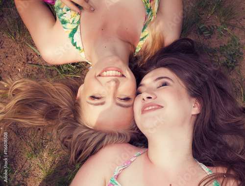 Happy teenagers friends lying on a grass laughing in a park photo