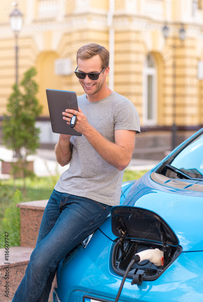 Man using tablet near eco car Man using tablet near eco car