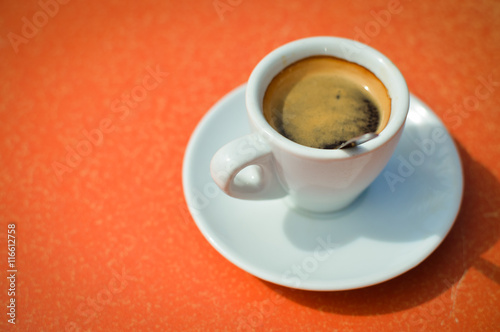 Closeup on cup of fresh espresso on table, view from above, bright background