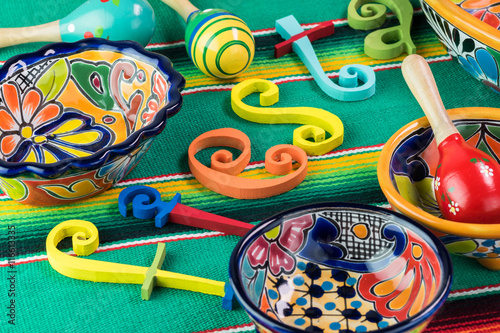 Mexican fiesta table decoration with colorful painted letters, bright pottery, maracas.