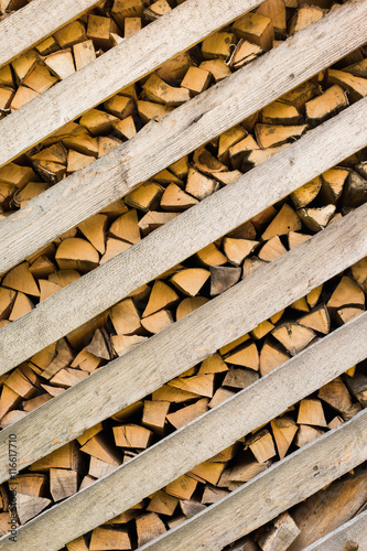 Brown color wood background. Vertical image of many dry chopped firewood in storage ready for use.