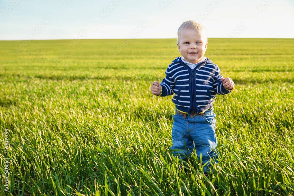 Beautiful baby boy standing in the green grass Beautiful baby boy standing in the green grass