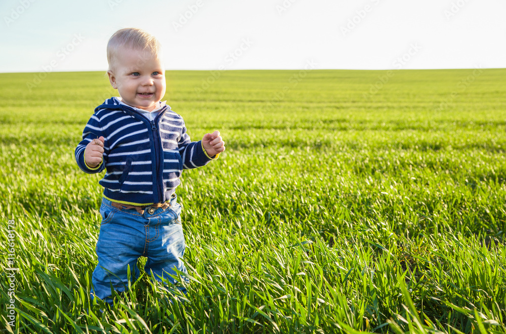 Beautiful baby boy standing in the green grass Beautiful baby boy standing in the green grass