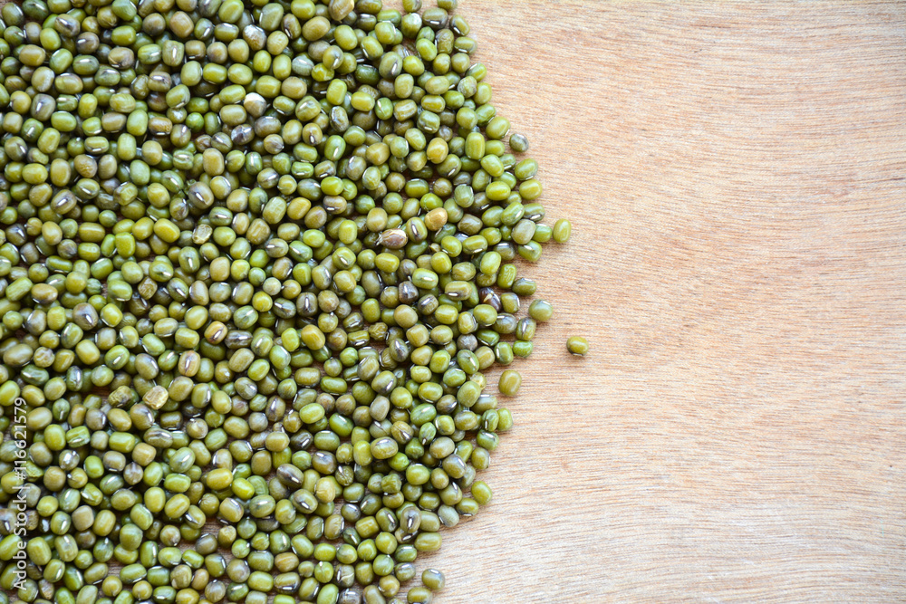 Green bean or mung bean seeds in a cup on a wooden floor. Green bean or mung bean seeds in a cup on a wooden floor.