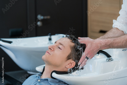 Close-up of a young man having his hair washed in hairdressing salon