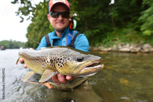 Fly fisherman holding brown trout out of water