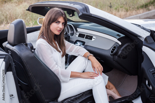 girl sitting in a white cabriolet with open door