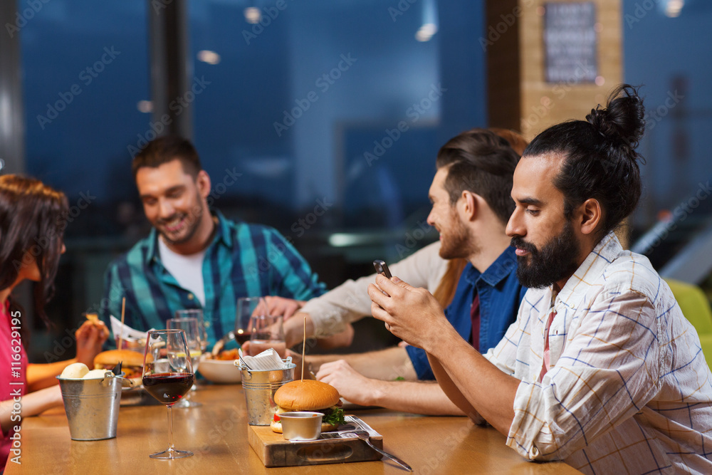 man with smartphone and friends at restaurant