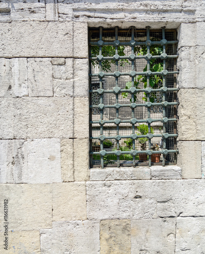 Old sandstone wall with window and grille
