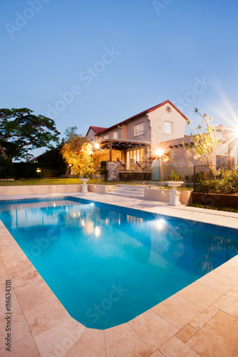Modern swimming pool with mansion at night with lights