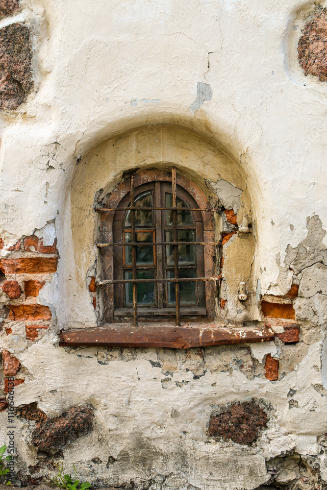 A semicircular window with bars in an old brick building