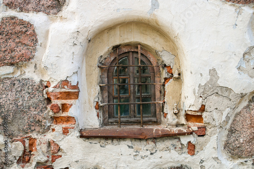 A semicircular window with bars in an old brick building