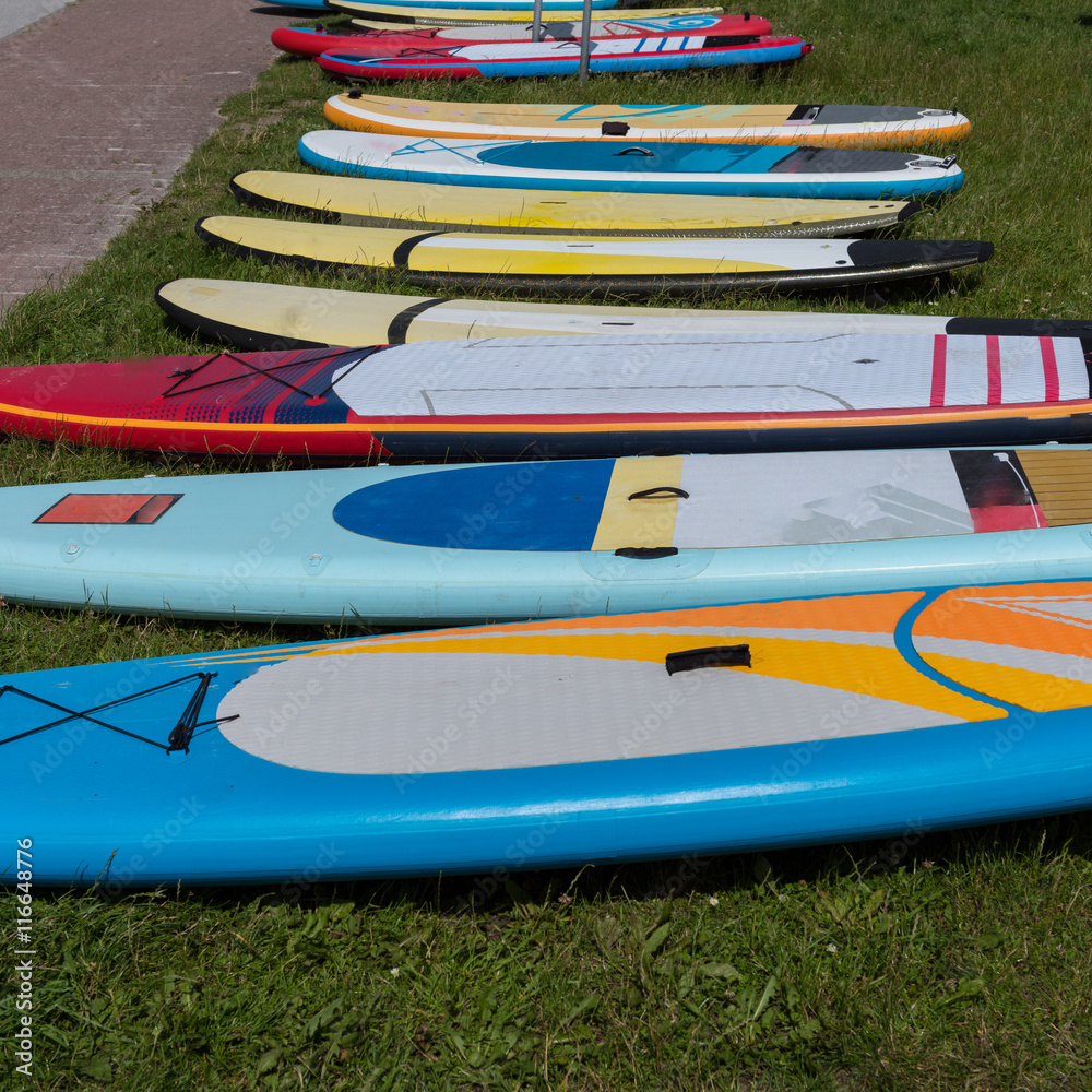colorful surf boards lying in the grass waiting to be used colorful surf boards lying in the grass waiting to be used