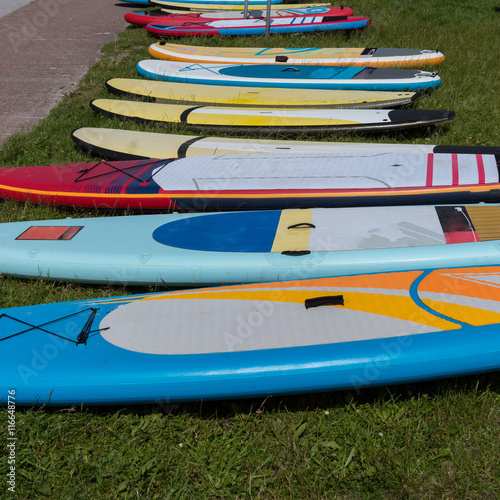 colorful surf boards lying in the grass waiting to be used