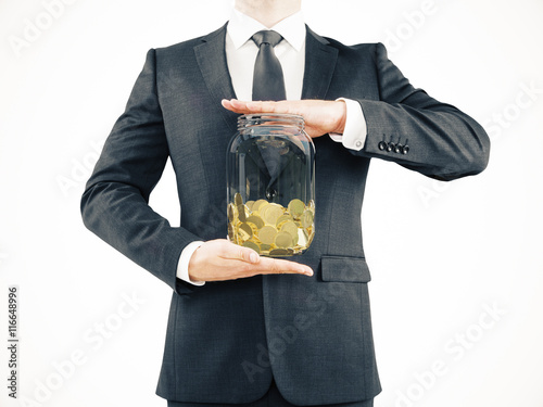 Businessman holding jar with coins