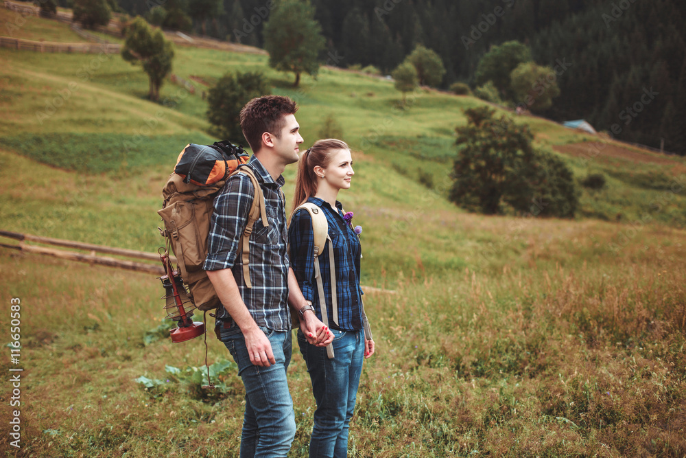 A couple of tourists in time of trip steel and admire the beautiful mountain scenery. The guy hugs the girl. The concept of love, tenderness and recreation