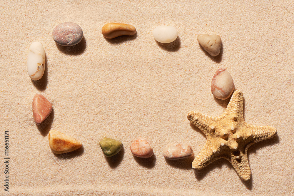 Rectangular frame of sea stones and starfish on sand Rectangular frame of sea stones and starfish on sand