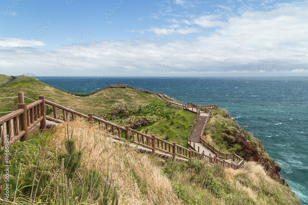 View of a coastal walkway next to the Songaksan Mountain on Jeju Island in South Korea.