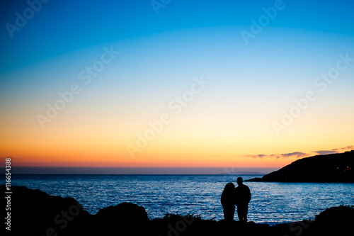 Silueta de una pareja frente al mar al anochecer