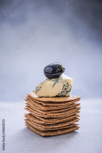 pile of crackers with brie and olive