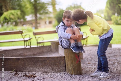 Slika na platnu Girl Supporting Sad Boy Sitting Alone on Playground