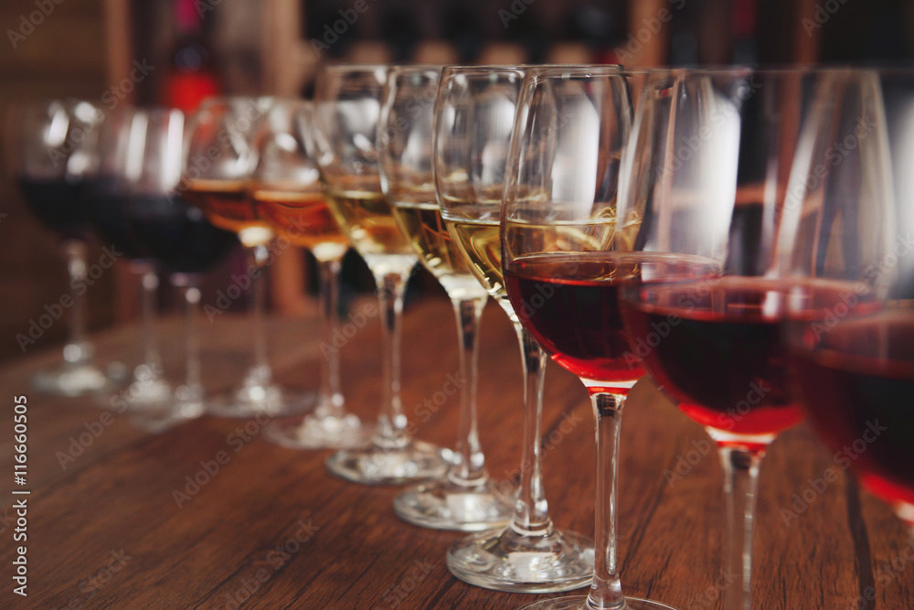 Many glasses of different wine in a row on bar counter