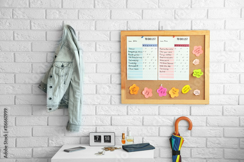 Wooden board with to do list hanging on white brick wall photo