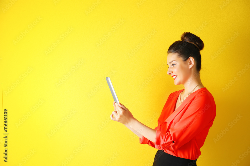 Pretty young woman holding tablet on yellow background Pretty young woman holding tablet on yellow background