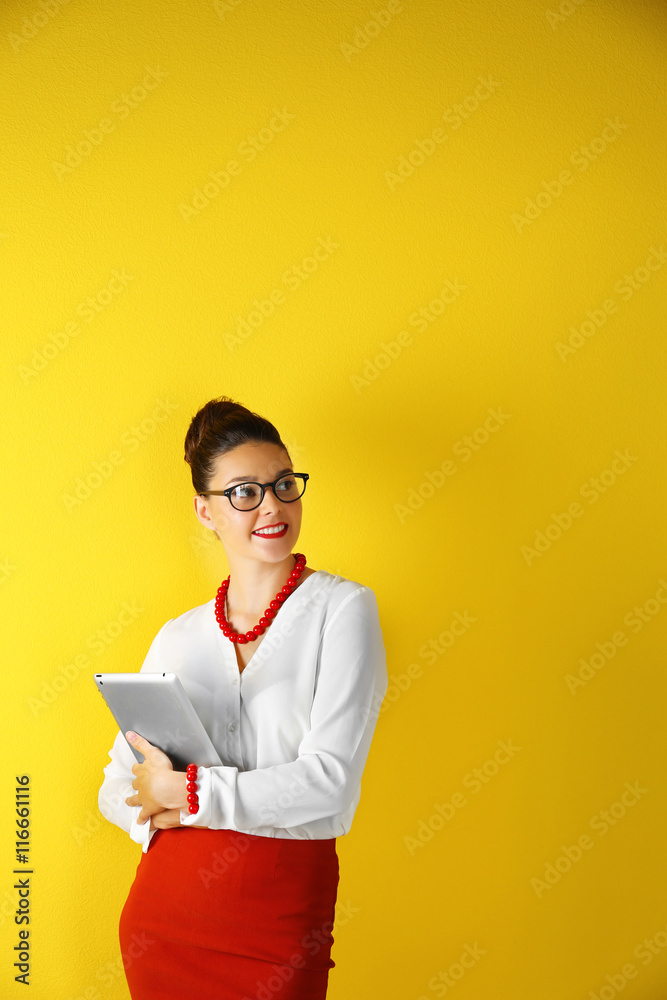 Pretty young woman holding tablet on yellow background Pretty young woman holding tablet on yellow background