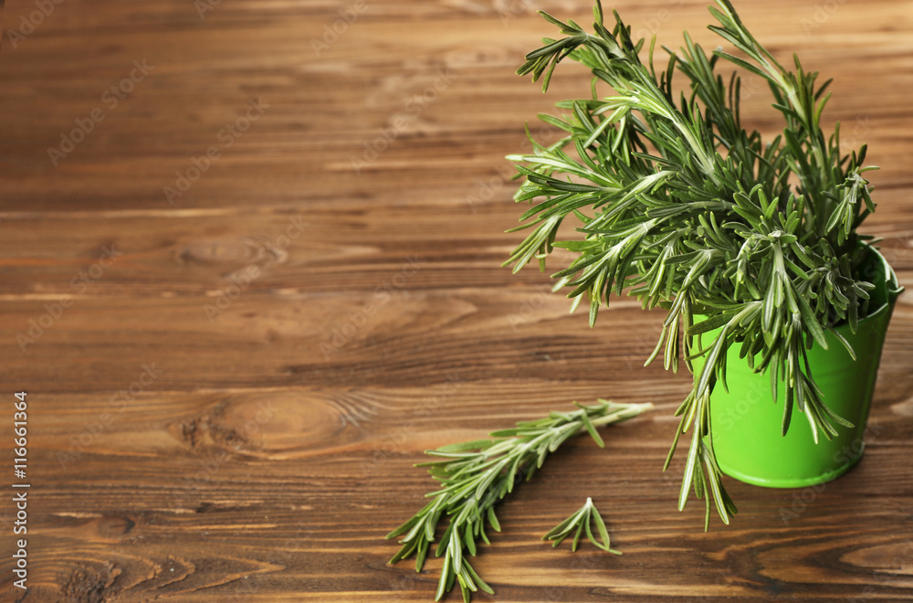 Fresh rosemary in bucket on wooden table