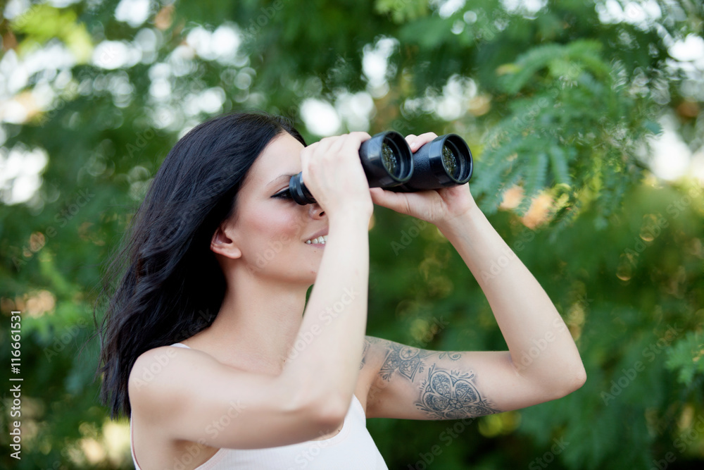 Brunette woman looking through the binoculars while strolling th Brunette woman looking through the binoculars while strolling th