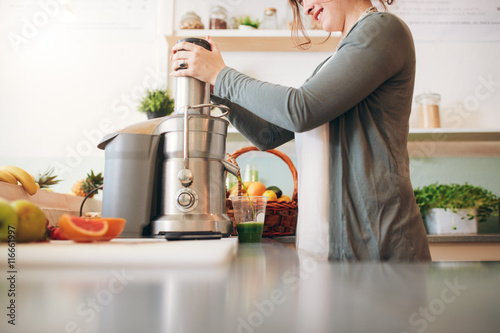 Fotografie Young female bar employee making fruit juice