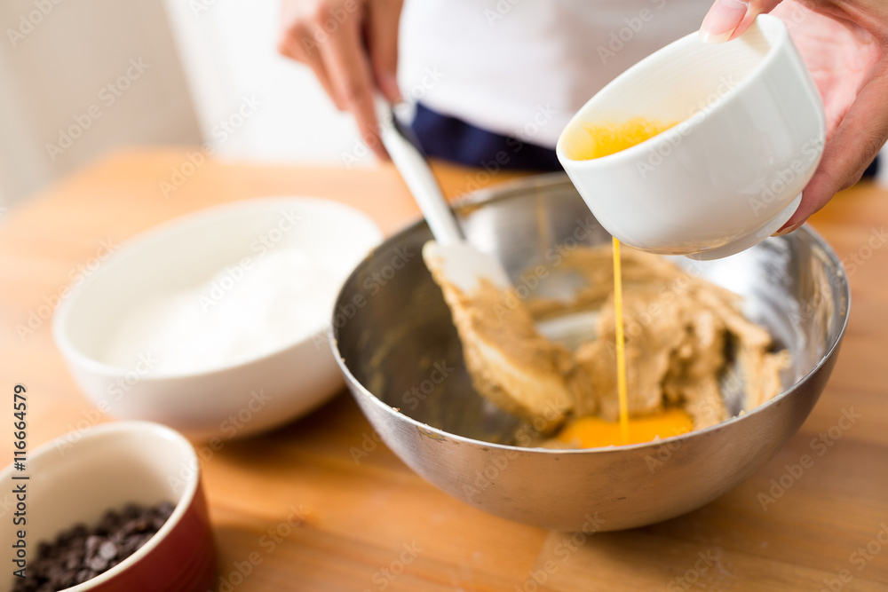 Woman mixing the paste with adding egg Woman mixing the paste with adding egg