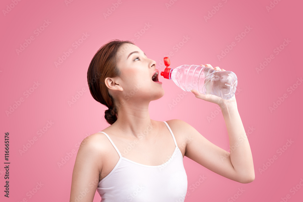 Cheerful beautiful sporty asian young woman holding a bottle of