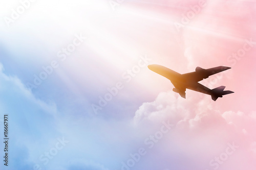 Fotografie Airplane in the sky and colorful clouds in sunset