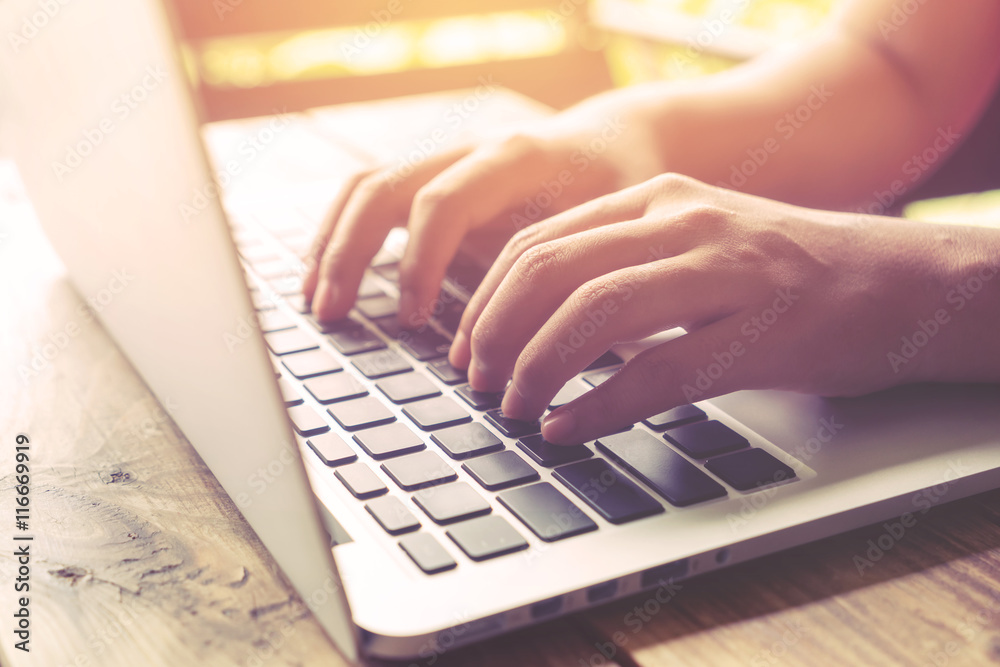 Side view shot of beautiful young hipster woman's hands busy working on her laptop sitting at wooden table in a coffee shop - retro filter effect and vintage color style Side view shot of beautiful young hipster woman's hands busy working on her laptop sitting at wooden table in a coffee shop - retro filter effect and vintage color style