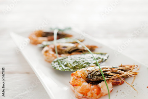 Grilled shrimp and stuffed mussel on white, close-up. Prepared mediterranean meal of fresh seafood