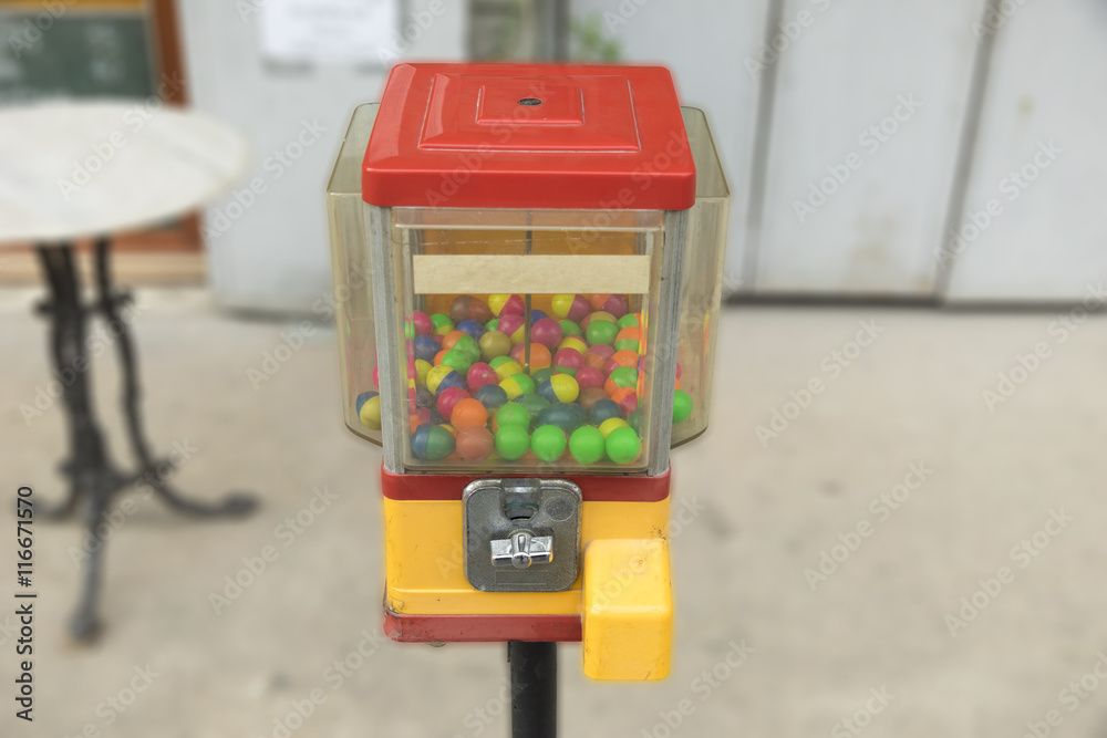 Old gumball machine on street background.