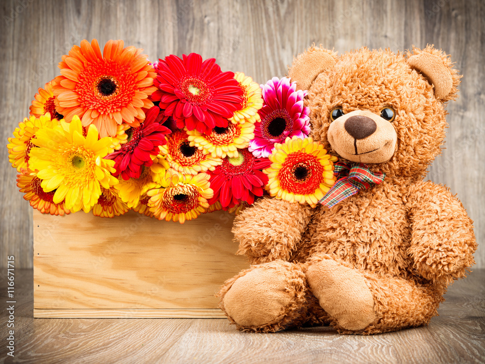Obraz premium Flowers and a teddy bear on wooden background